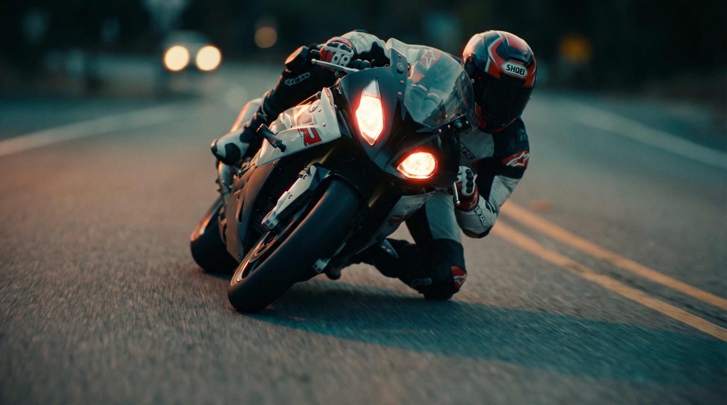 A motorcycle racer leans into a sharp turn on a dusky highway